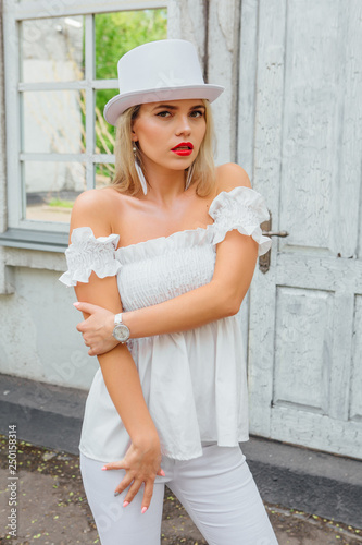 Sexy modern bride in white cylinder hat standing next to old vintage door and mirror window. © Smile
