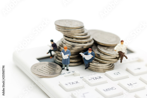 Miniature people: Businessman reading book on calculator and coins, Business and finance investment concept photo