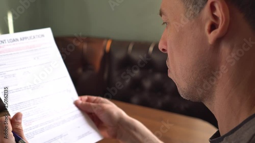 Mature man reading credit application form on a paper sheet photo