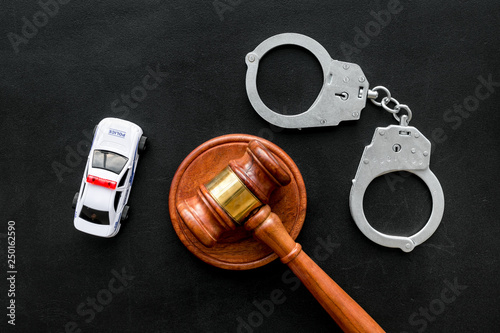 Crime concept. Police car toy, handcuff, judge hammer on black background top view