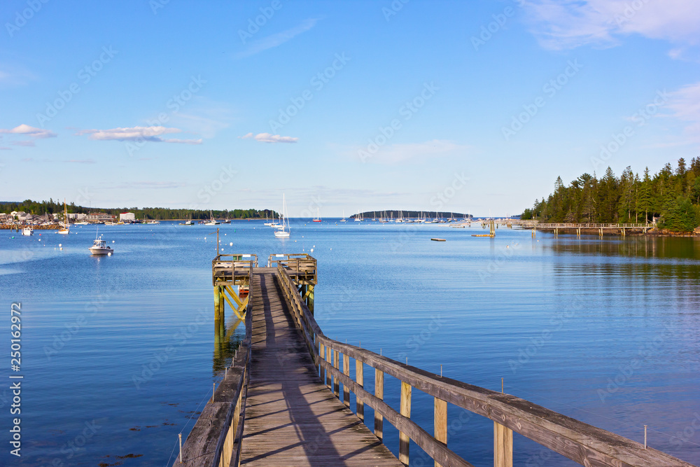 A wooden pier at Bar Harbor, Maine, USA. Scenic panorama with yachts and motorboats on quiet waters of the harbor.