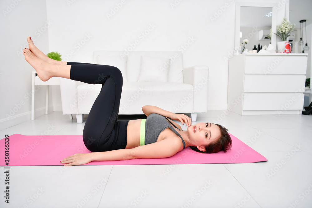 Fototapeta premium Concept of exercise. Beautiful girl is exercising in her house. Beautiful girl takes good care of her health.