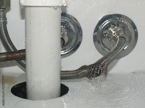 Ruptured hose leaking water in bathroom