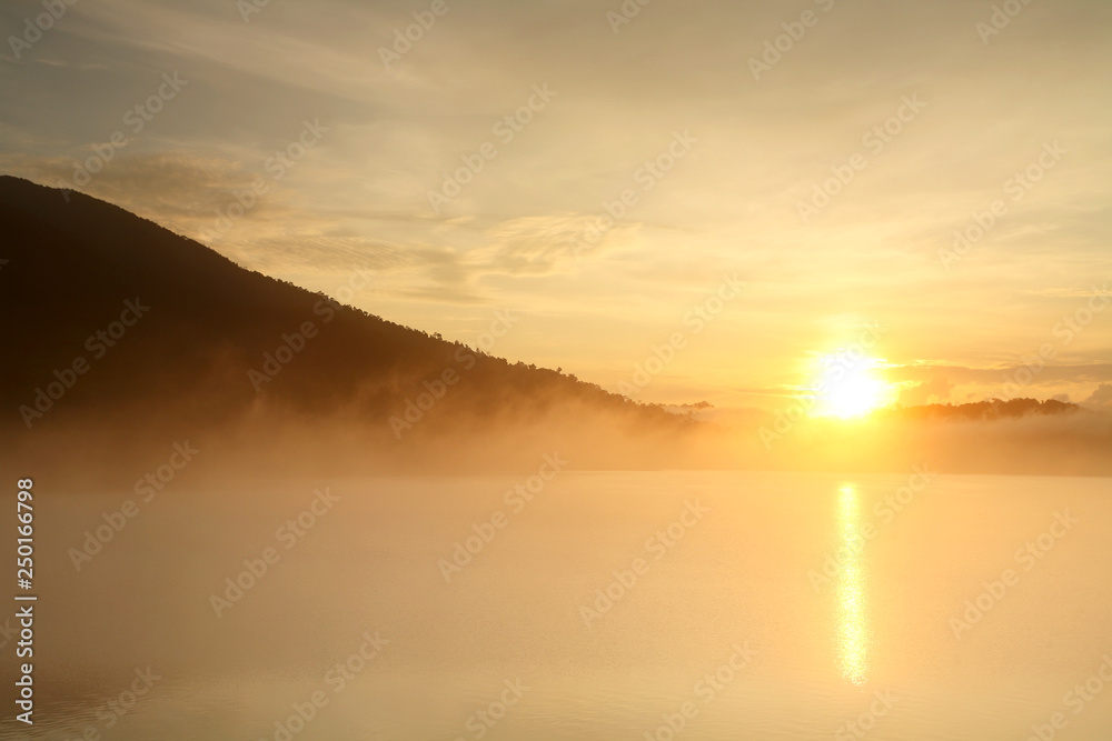 Beautiful landscape with fog and mountain at water dam in the during the sunrise of Thailand