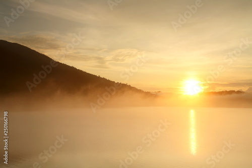Beautiful landscape with fog and mountain at water dam in the during the sunrise of Thailand