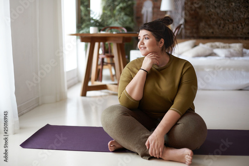 Young woman sitting on yoga mat photo