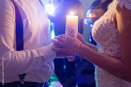 bride and groom hold a candle in hand