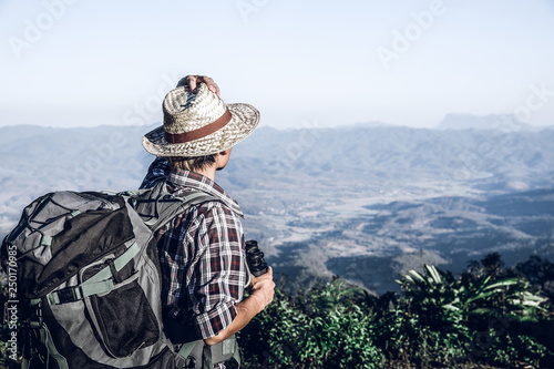 young hiker with backpack holding binoculars on the mountain. travel concept.