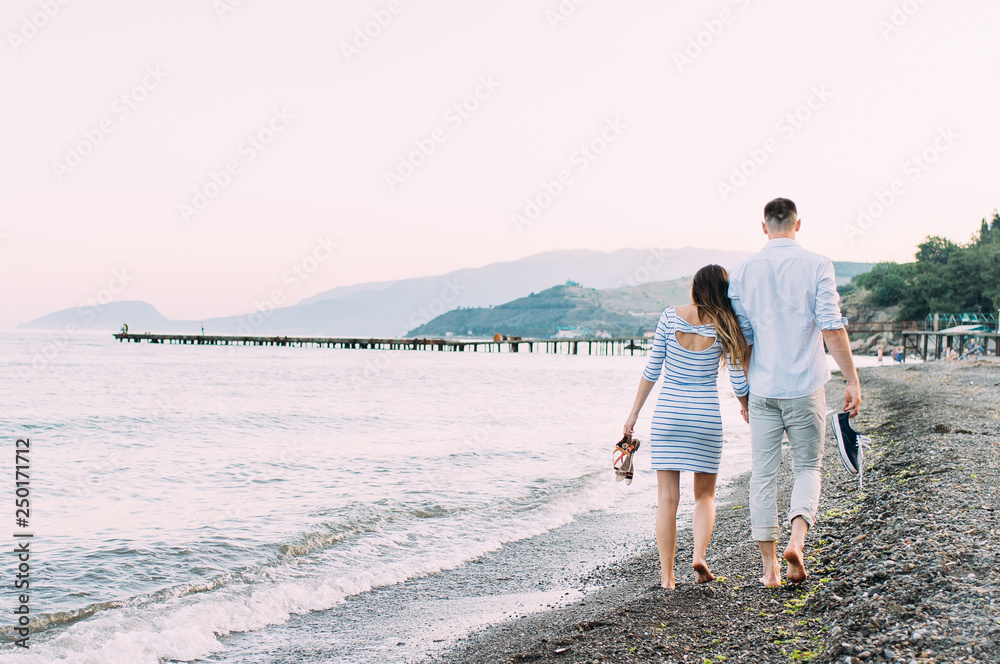 Young couple walking barefoot on the beach