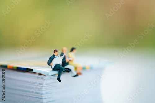 Miniature people: Small businessmen sitting on paper book. Education, Money, Financial and Business Growth concept. © Khongtham