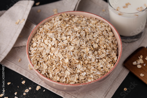 Oatmeal in a plate and a cup of milk on a towel on black background. Healthy food. close up © Sergey