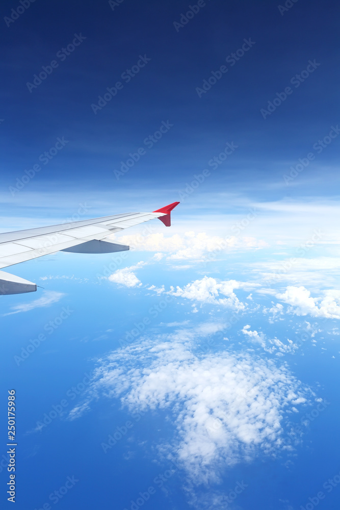 View from airplane window with blue sky and white clouds, select focus with shallow depth of field. Beautiful natural cloudscape