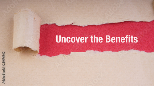 Foto UNCOVER THE BENEFITS text on brown envelope and torn paper