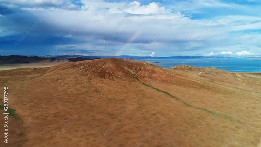 Mongolia, Lake Telmen-Nuur surrounded by desert mountains. Aerial shot of the rainbow between the clouds Mongolia, Lake Telmen-Nuur surrounded by desert mountains. Aerial shot of the rainbow between the clouds