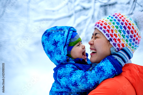 An Asian woman mother and her baby boy are playing in a snowy park in winter