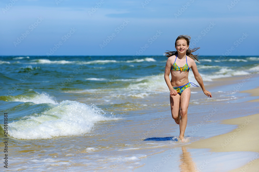 Little girl in swimsuit running on the beach