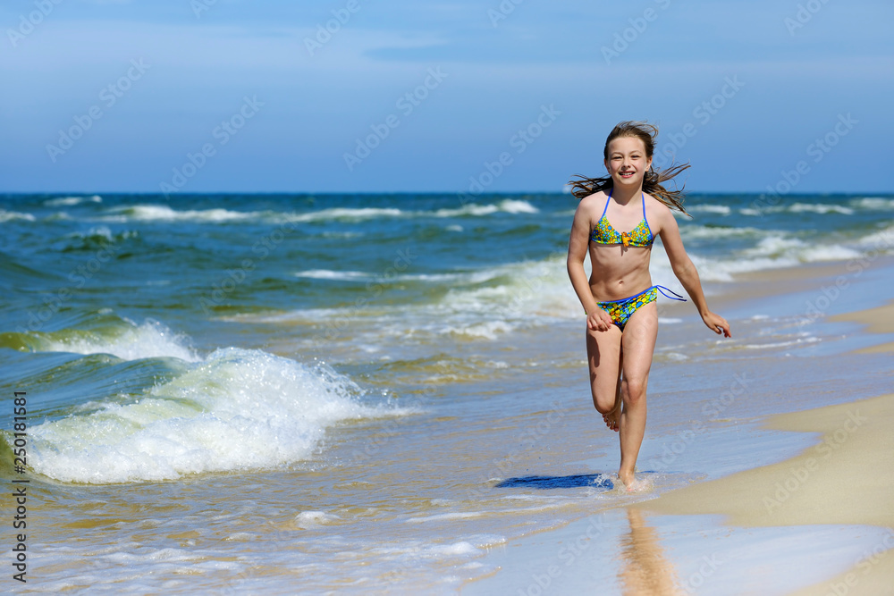 Little girl in swimsuit running on the beach Little girl in swimsuit running on the beach
