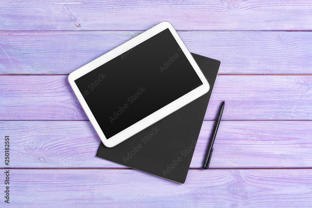 Digital tablet and notepad office on purple wooden background Digital tablet and notepad office on purple wooden background