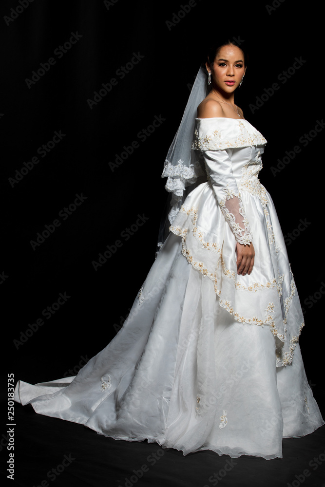 Lovely Asian Beautiful Woman bride in white wedding gown dress with lace veil, black hair, studio lighting black gradient background isolated copy space, sweet romantic soft alone bridal concept