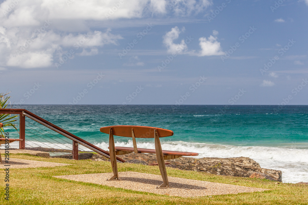 Empty park bench overlooking turquoise ocean water Empty park bench overlooking turquoise ocean water