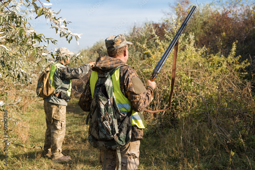 Hunter with a gun and a dog go on the first snow in the steppe, Hunting pheasant in a reflective vest Hunter with a gun and a dog go on the first snow in the steppe, Hunting pheasant in a reflective vest