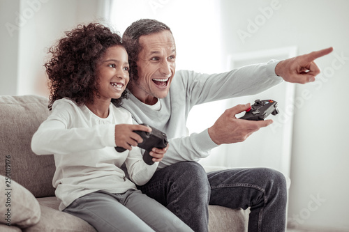 Excited cheerful daughter and father playing together at home