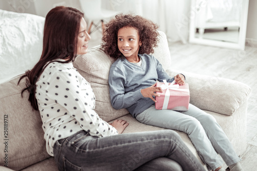 Attractive nice woman sitting on the sofa together with a girl