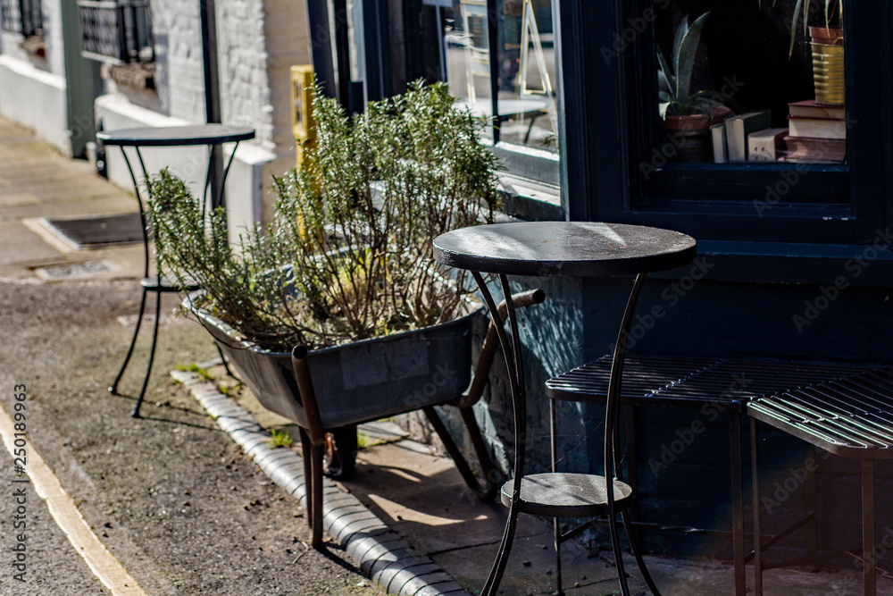 Outside tables and a wheel barrow used as a plant pot outside a quaint property in a traditional English market town