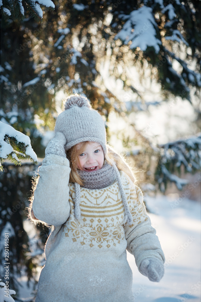 little cheerful girl in the snowy woods. Sunny winter day.