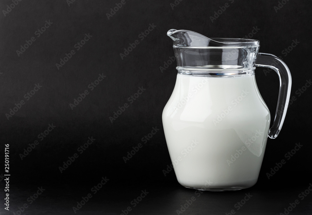 Glass jug of milk on black background with copy space Glass jug of milk on black background with copy space