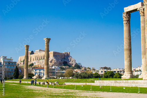 View of the ancient columns of Zeus's temple with the Acropolis and Parthenon temple in the background in Athens Greece.