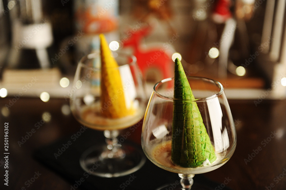 Food styling of Italian dessert afogato as Christmas tree with shining star. Inverted green waffle cone in cognac glass