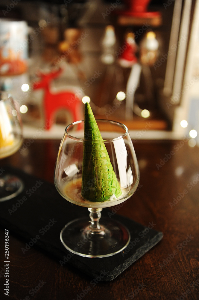 Fototapeta premium Food styling of Italian dessert afogato as Christmas tree with shining star. Inverted green waffle cone in cognac glass