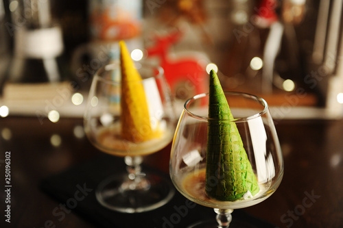 Food styling of Italian dessert afogato as Christmas tree with shining star. Inverted green waffle cone in cognac glass