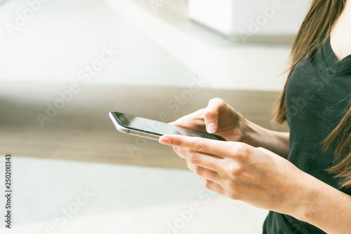 Closeup shot of a woman typing on mobile phone. Girl s hand holding a modern smartphone and pointing with figer. Looking on screen with webpage or message. 