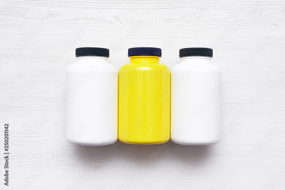 Sport nutrition jars on a white wooden table background. Sport nutrition jars on a white wooden table background.