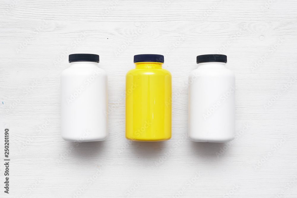 Sport nutrition jars on a white wooden table background.