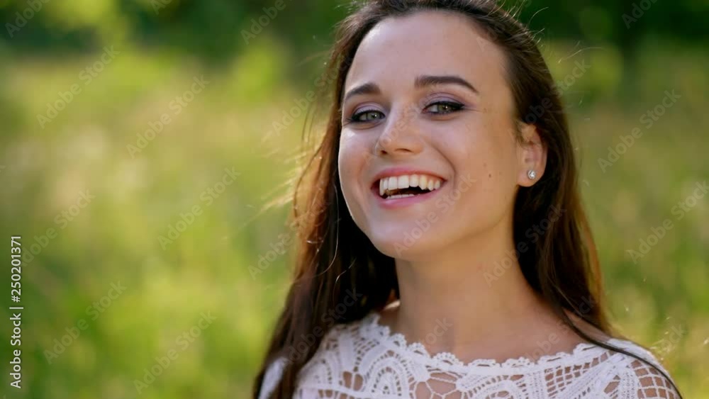 Charming woman in a white dress smiles at camera. Close-up Charming woman in a white dress smiles at camera. Close-up