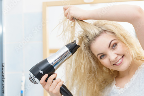 Blonde woman using hair dryer