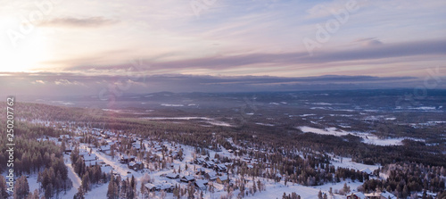 Panorama aerial view of Idre Fjäll cabins during sunrise a clear winter day in Sweden with one of the slopes in the photo. 