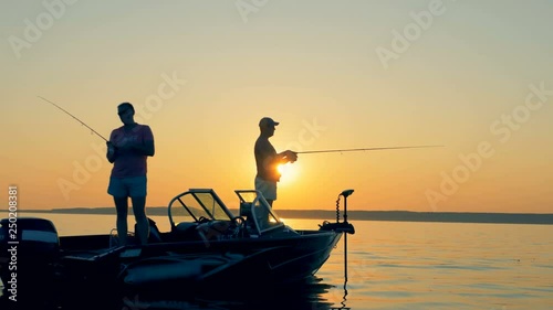 People fishing on a boat. Two fishermen on a small boat. photo