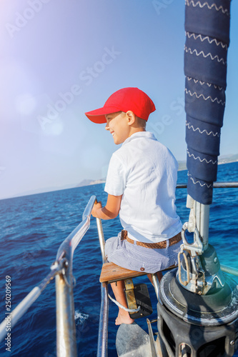 Little boy on board of sailing yacht on summer cruise. Travel adventure, yachting with child on family vacation.