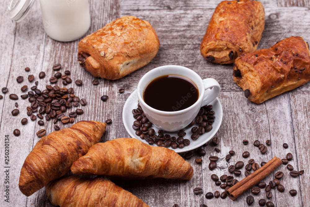 Breakfast with fresh coissants with coffe and milk on rustic wooden table
