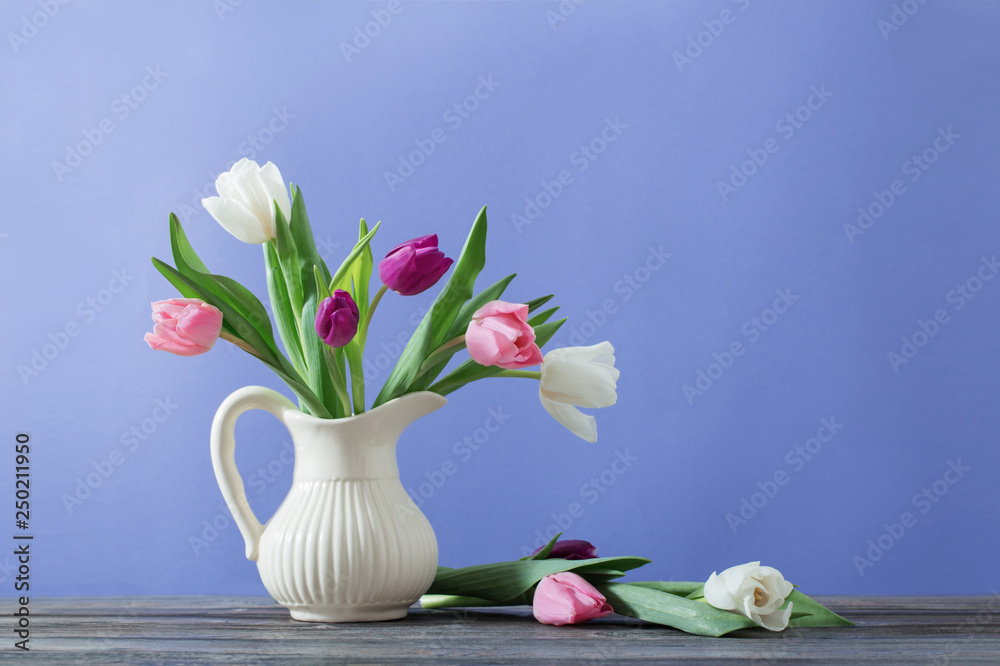 Obraz premium tulips in jug on violet background