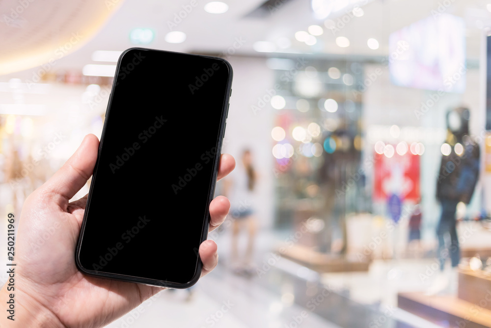 Close-up of female use smartphone blurred images in the mall and Clothes shop blur of the background.