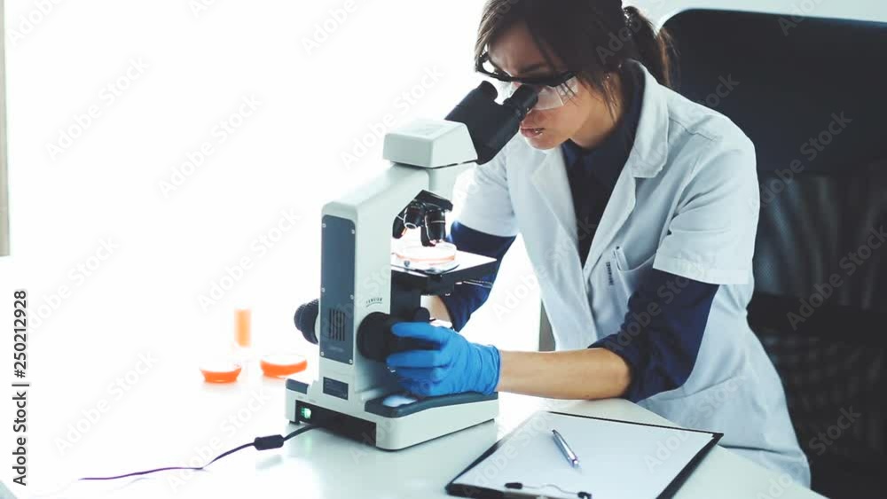 Young scientist looking through a microscope in a laboratory. Young scientist doing some research.