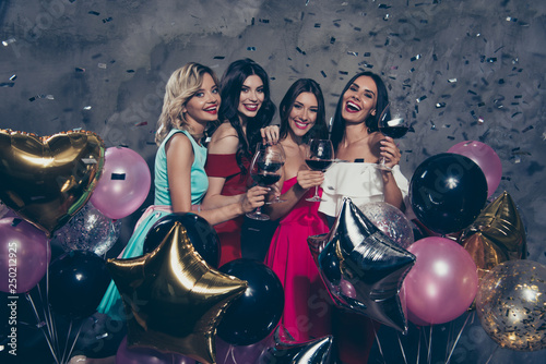 Four nice-looking magnificent lovely fascinating chic attractive gorgeous cheerful cheery ladies enjoying red wine flying decorative elements having fun over gray concrete wall photo