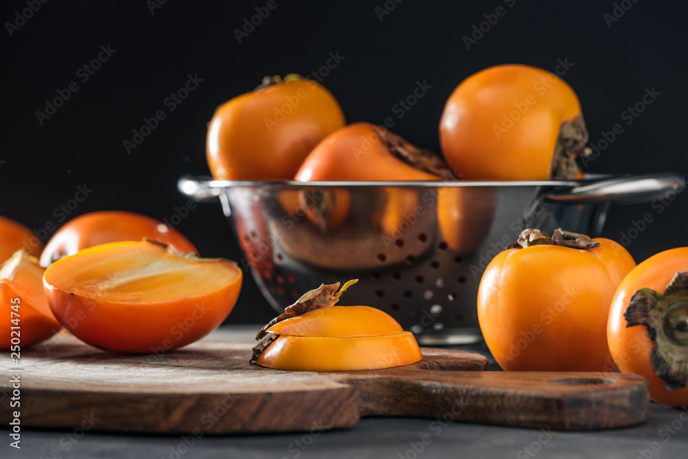 selective focus of orange persimmons on cutting board and in colander
