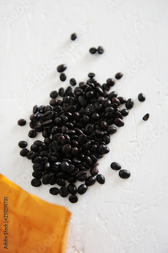Coffee beans roasted in the Spanish way torrefacto with sugar. Poured out of the package on the table, close-up. photo