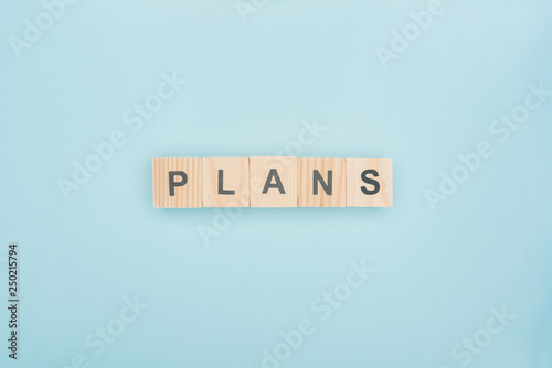 top view of plans lettering made of wooden blocks on blue background